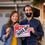 couple with sold house sign