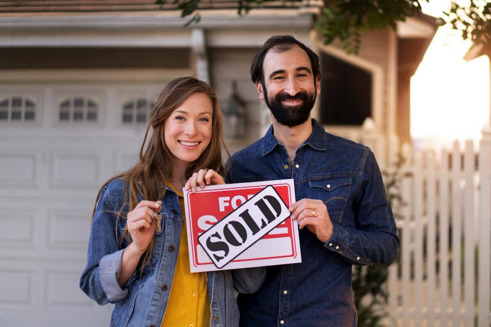 couple with sold house sign