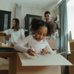 family with boxes in new home little girl writing