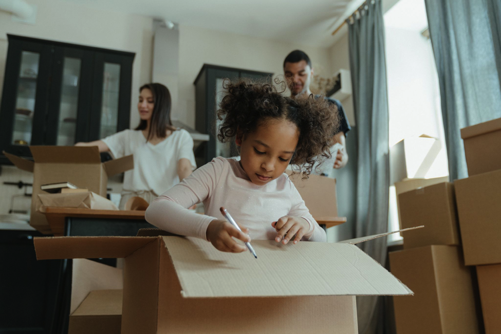 family with boxes in new home little girl writing